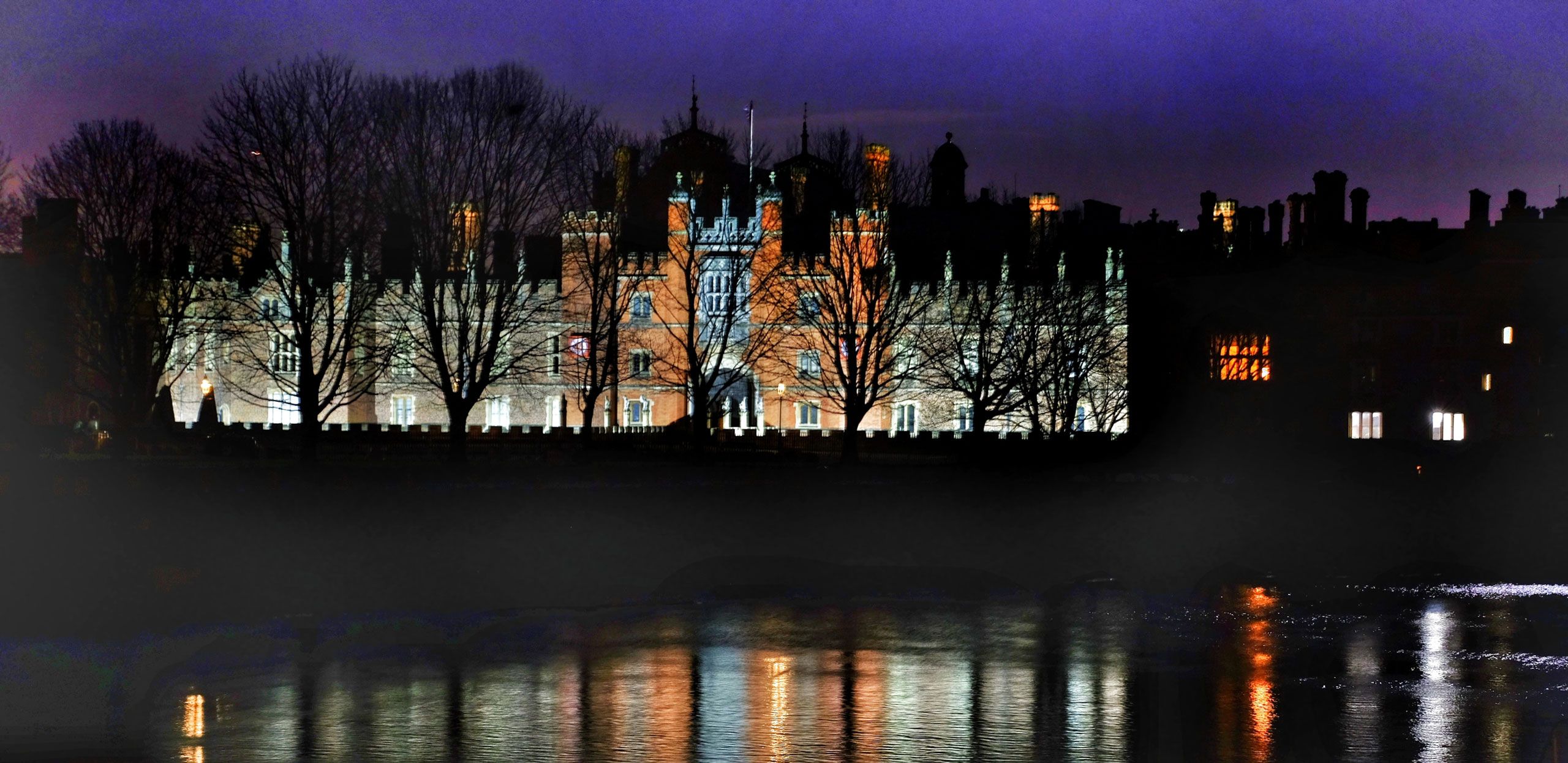 A view across the Thames to Hampton Court Palace at night image.